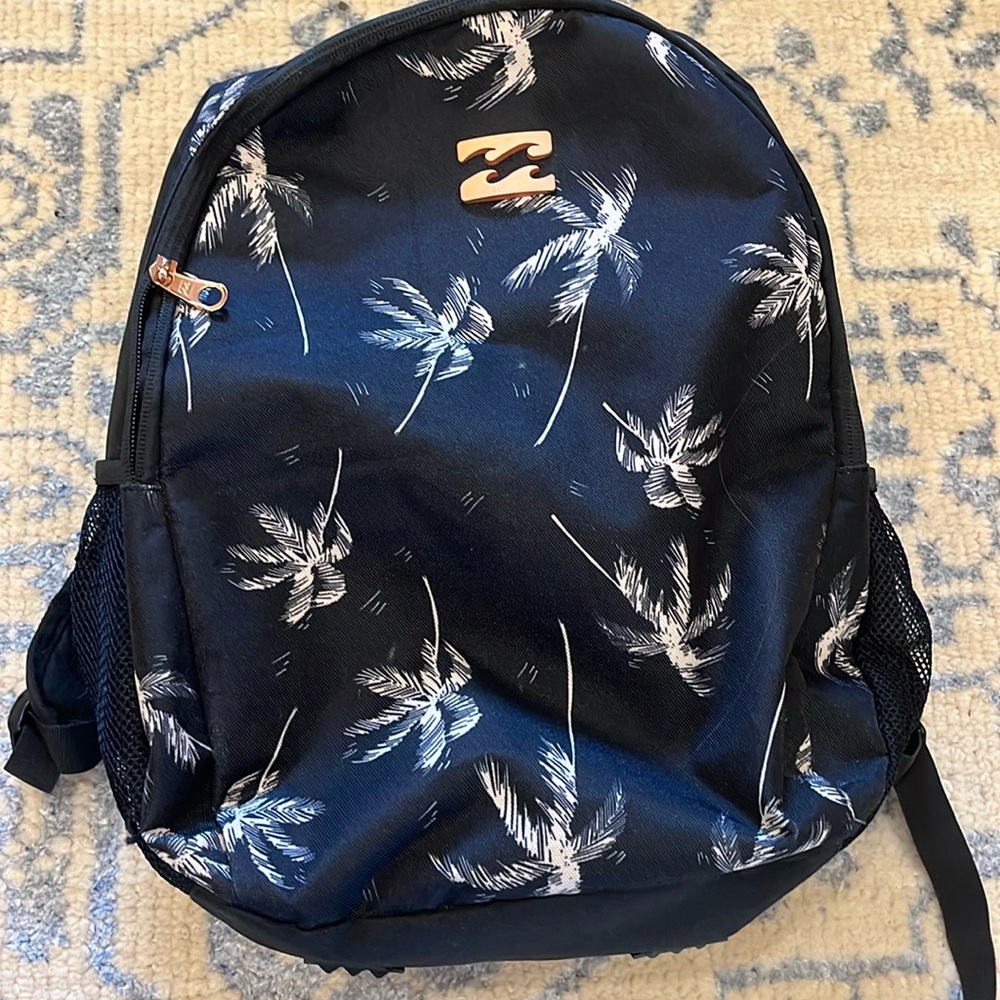 Black Billabong backpack with white palm trees and rose gold zippers.